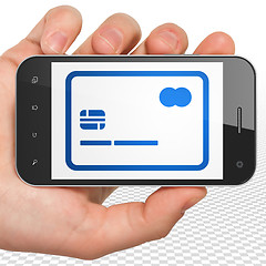 Image showing Finance concept: Hand Holding Smartphone with Credit Card on display