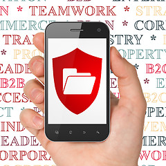 Image showing Business concept: Hand Holding Smartphone with Folder With Shield on display