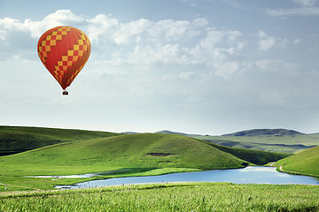 Image showing Air balloon flying over the meadows with lake