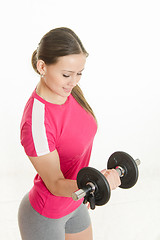 Image showing Sportswoman looking at dumbbell in the right hand