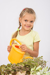 Image showing Happy little girl watering flowers watering