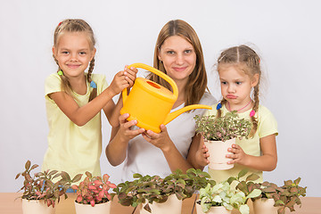 Image showing Fun and funny mom and daughter watered flowers