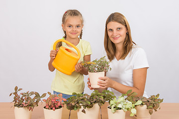 Image showing Mom and daughter take care of potted flowers