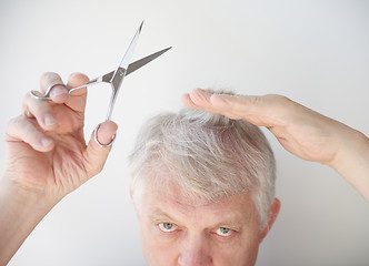 Image showing Senior man cuts hair.  