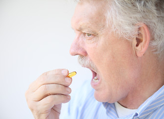 Image showing senior takes fish oil supplement 