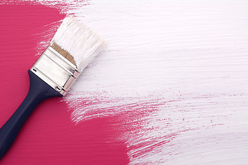Image showing Paintbrush with white paint painting over pink