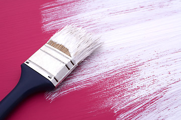 Image showing Dirty paintbrush with white paint on half-painted board