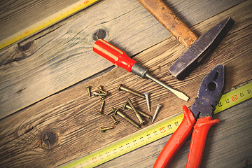 Image showing Old hammer, pliers, yellow measuring tape, vintage screwdriver a