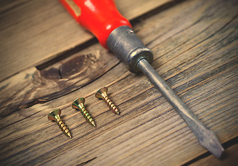 Image showing screws and old screwdriver with a red wooden handle