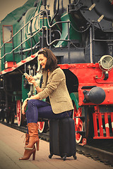 Image showing woman sitting on a trunk road and uses the phone