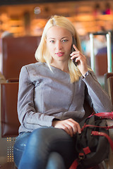 Image showing Female traveler using cell phone while waiting.