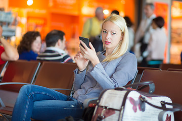 Image showing Female traveler using cell phone while waiting.