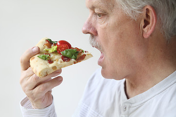 Image showing man eats BLT pizza profile view 