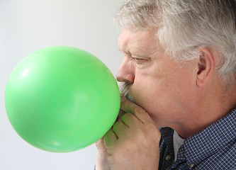 Image showing senior man blowing up balloon