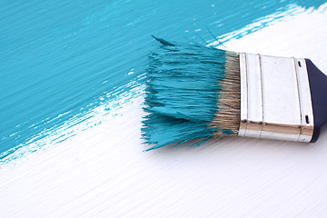 Image showing Close-up of paintbrush painting a white board blue