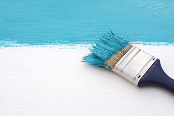 Image showing Paintbrush with blue paint, painting over white board