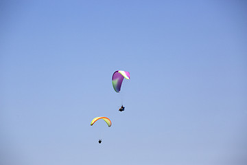 Image showing Colorful paragliders with blue sky