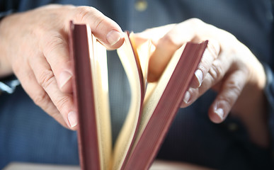 Image showing Man turns pages of book.