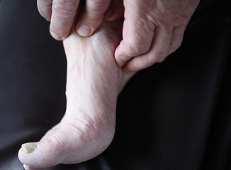 Image showing man checks his sore foot	