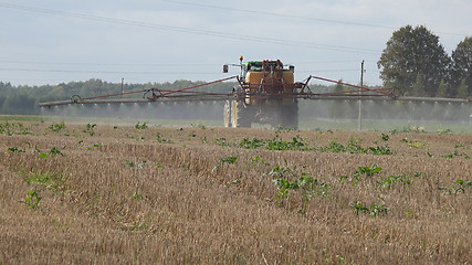 Image showing Tractor spray stubble field with herbicide chemicals in autumn 