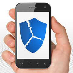 Image showing Security concept: Hand Holding Smartphone with Broken Shield on display