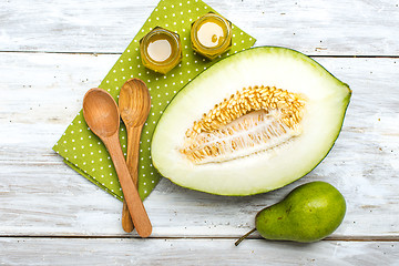 Image showing Cut melon green pear and honey on white board