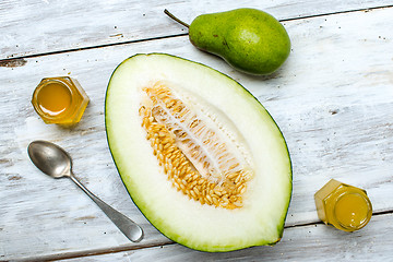 Image showing Tasty pear with melon and honey on rustic board