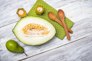 Image showing Cut melon green pear and honey on rustic board