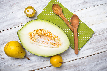 Image showing Melon with honey and two yellow pears on wood