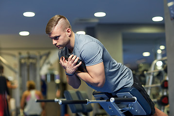 Image showing young man flexing back muscles on bench in gym