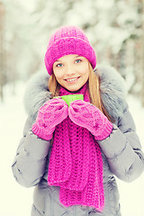 Image showing smiling young woman with cup in winter forest