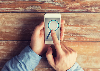 Image showing close up of hands with magnifier on smartphone