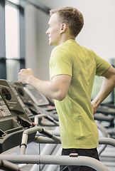 Image showing smiling man exercising on treadmill in gym