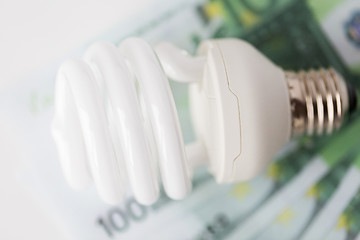 Image showing close up of euro money and light bulb on table