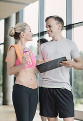 Image showing smiling young woman with personal trainer in gym