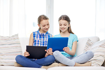 Image showing happy girls with tablet pc sitting on sofa at home