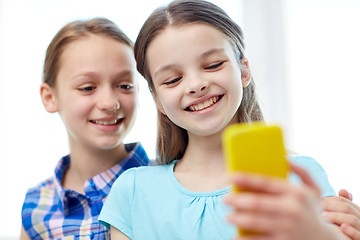 Image showing happy girls with smartphone taking selfie at home