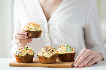 Image showing close up of woman with glazed cupcakes or muffins