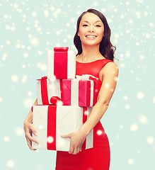 Image showing smiling woman in red dress with many gift boxes