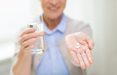 Image showing close up of senior woman with water and pills