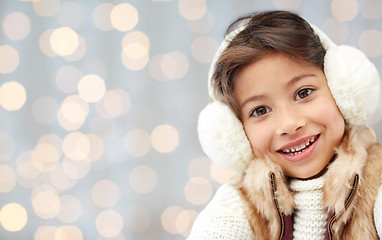 Image showing happy little girl in earmuffs over holidays lights