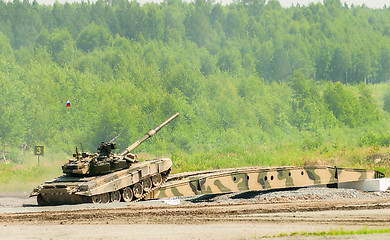 Image showing T-80 tank drives on bridge induced through obstacle