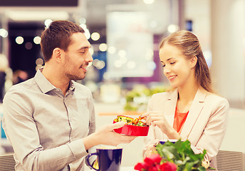 Image showing happy couple with present and flowers in mall