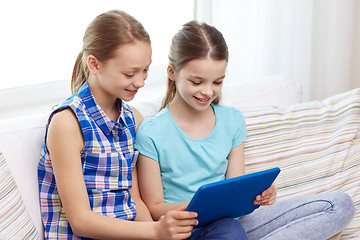 Image showing happy girls with tablet pc sitting on sofa at home