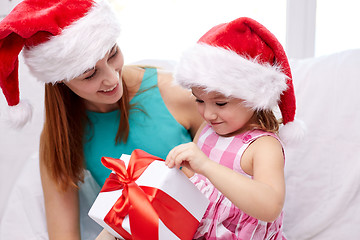 Image showing happy mother and child in santa hats with gift box