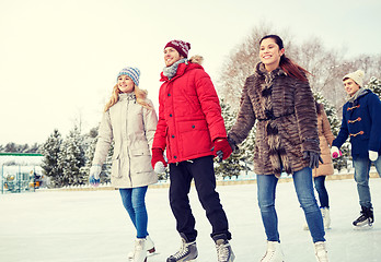 Image showing happy friends ice skating on rink outdoors