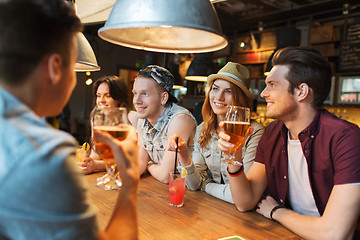 Image showing happy friends with drinks talking at bar or pub