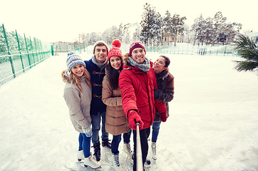 Image showing happy friends with smartphone on ice skating rink