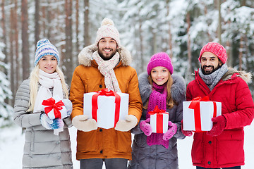 Image showing happy friends with gift boxes in winter forest