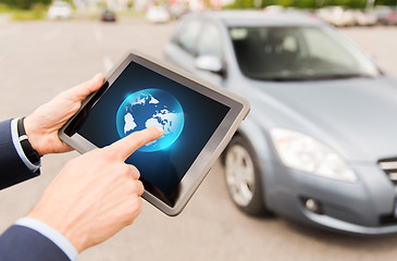 Image showing close up of male hands with tablet pc and car